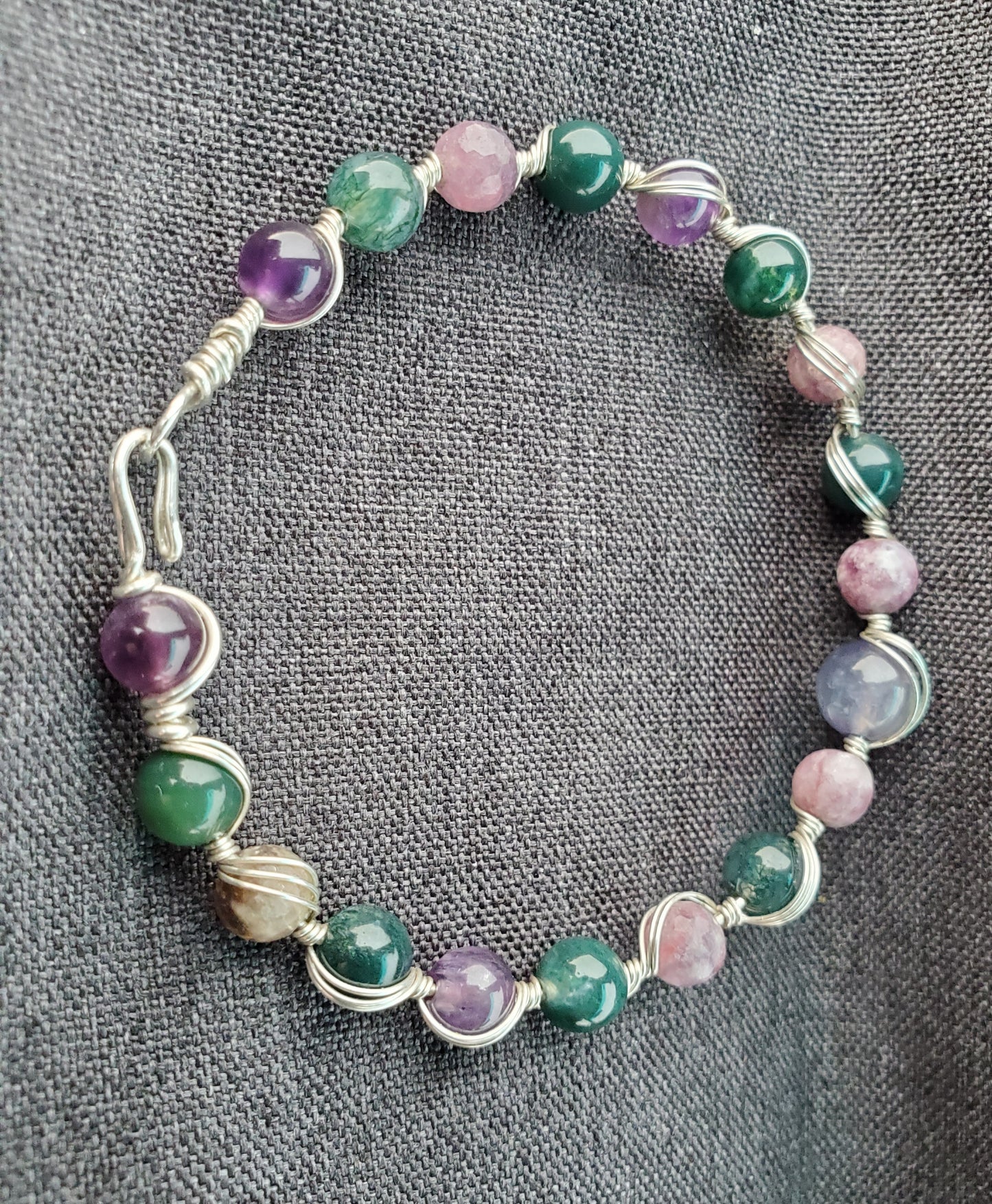 Sterling silver wire wrapped bracelet with tanzanite, tourmaline, moss agate, and amethyst.